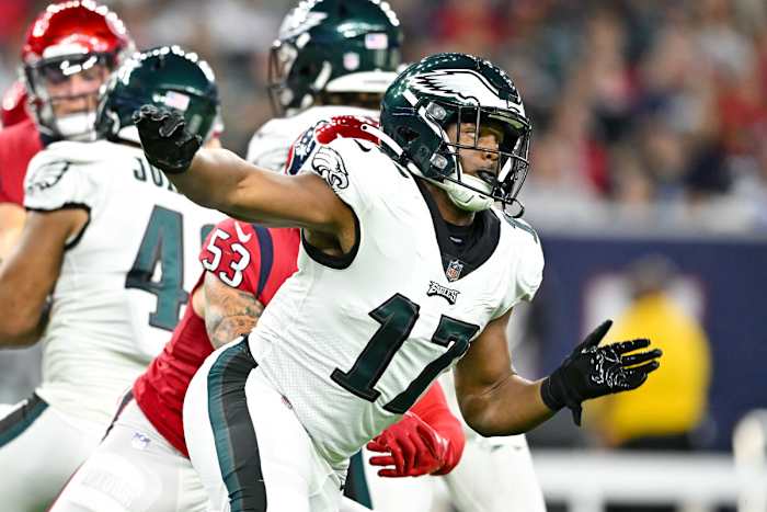 Nakobe Dean runs forward with his arms spread out